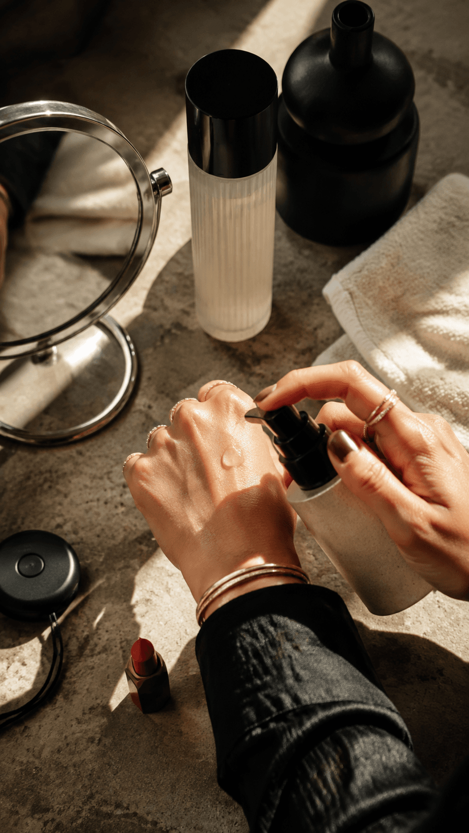 Temporary overhead beauty flat-lay: hands opening a skincare bottle among product bottles